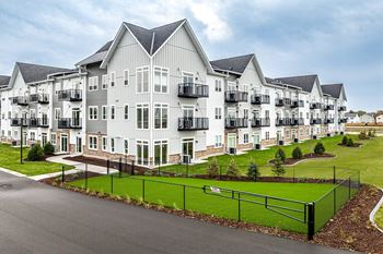 an exterior view of a large apartment building with a green lawn